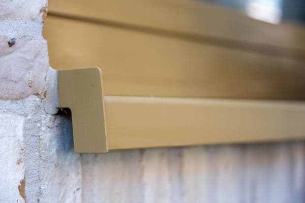 Champagne aluminium vensterbank met kopschot, close-up op een witgewassen baksteengevel